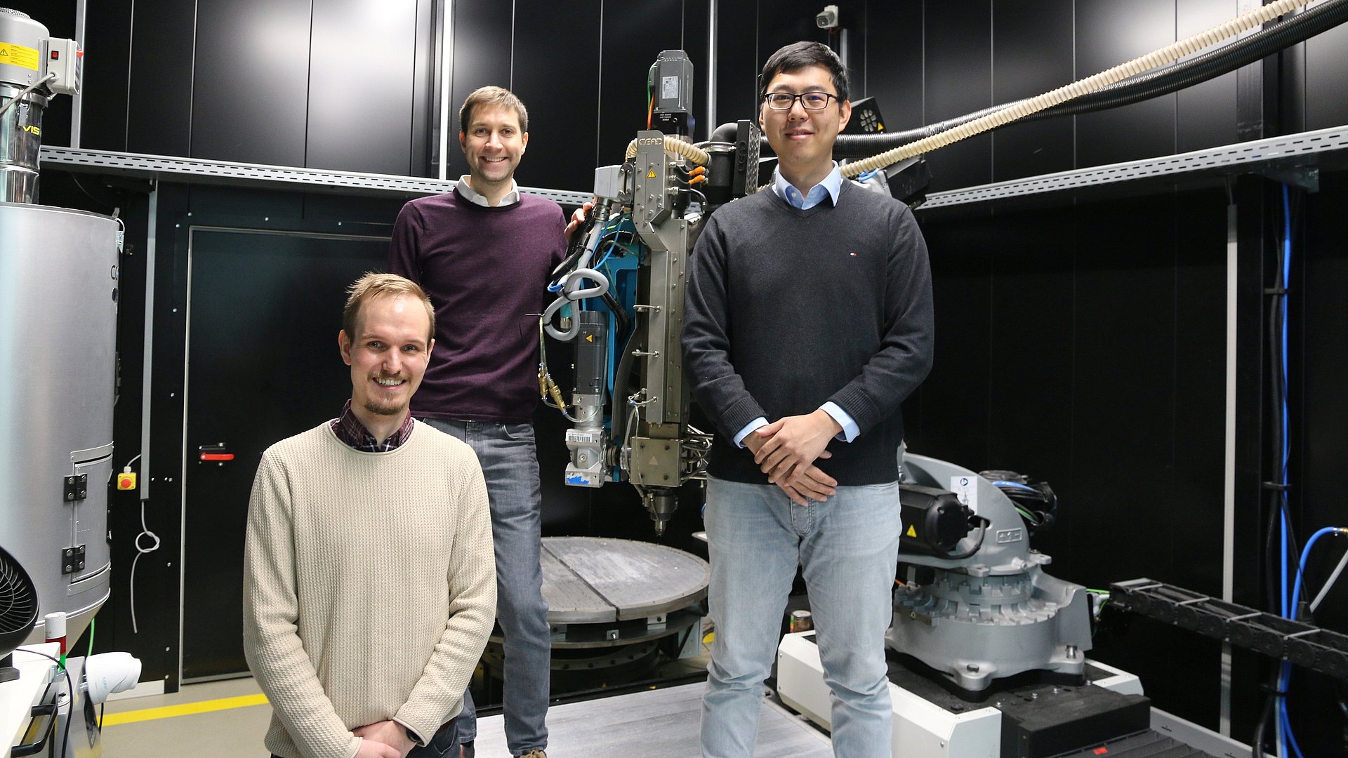 The three founders stand around a 3D printer with their technology.