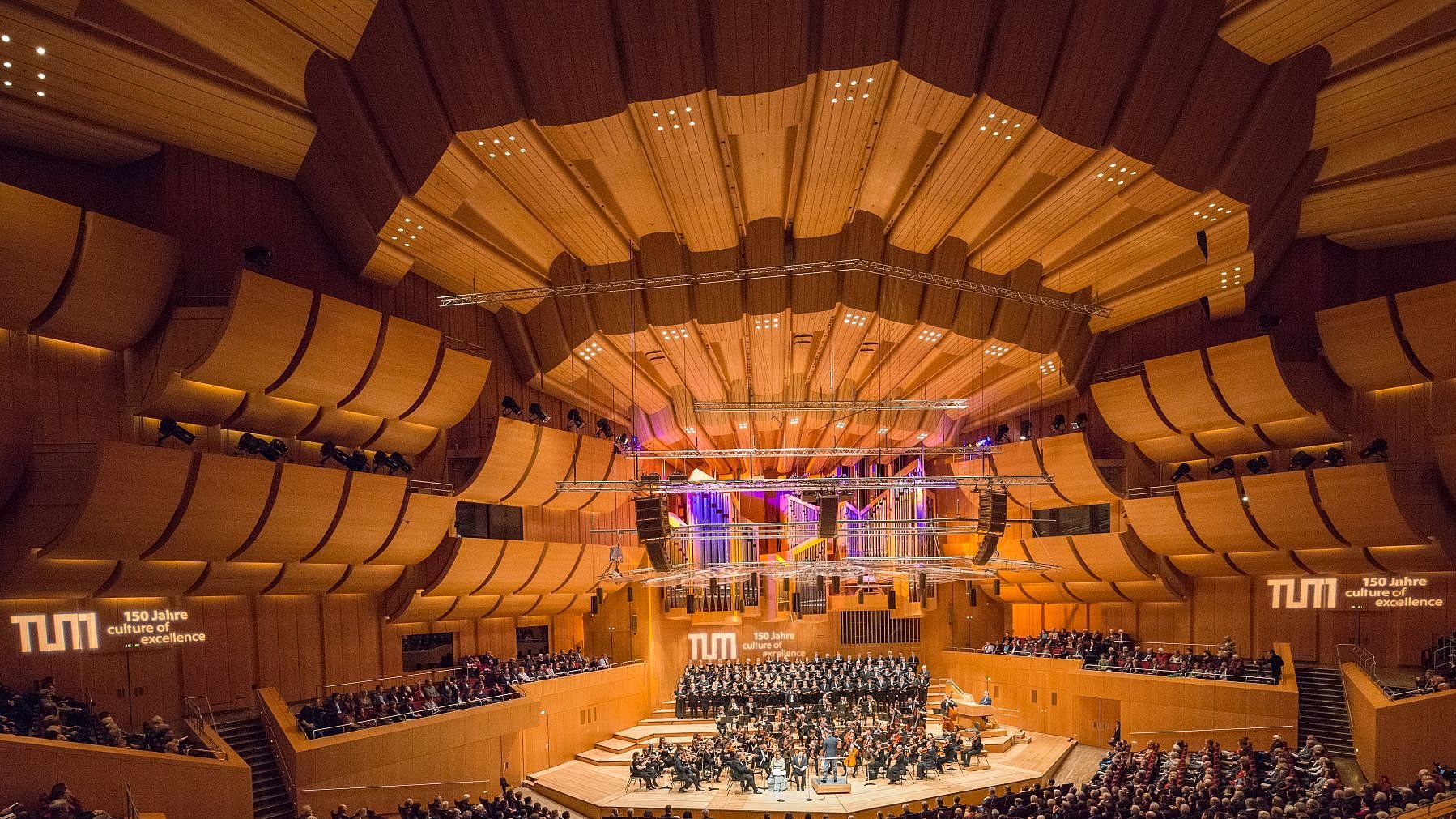 Concert hall of the Philharmonic Orchestra in Munich's Gasteig cultural center with visitors, orchestra, and choir. The Advent matinee also marks the start of celebrations for the anniversary of TUM's founding.