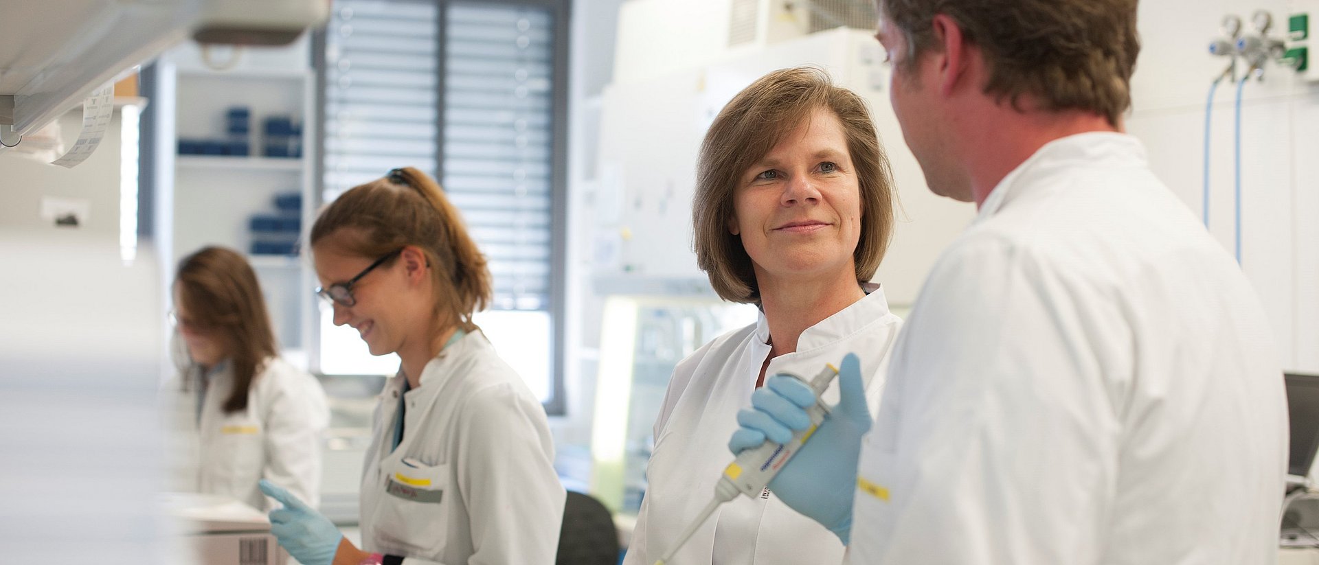 Prof. Ulrike Protzer mit Mitarbeitenden im Labor.