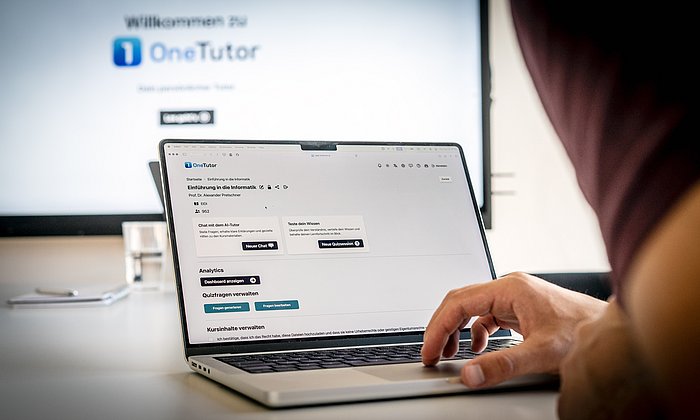 A look over the shoulder of a student who is sitting at a PC and working with the OneTutor tool.