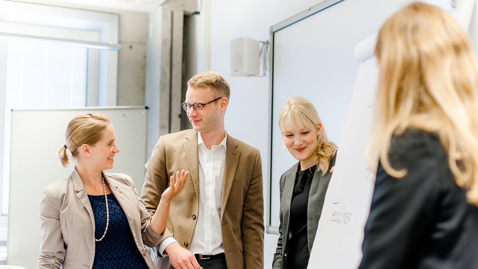 Three women and one man exchange ideas in front of a flipchart