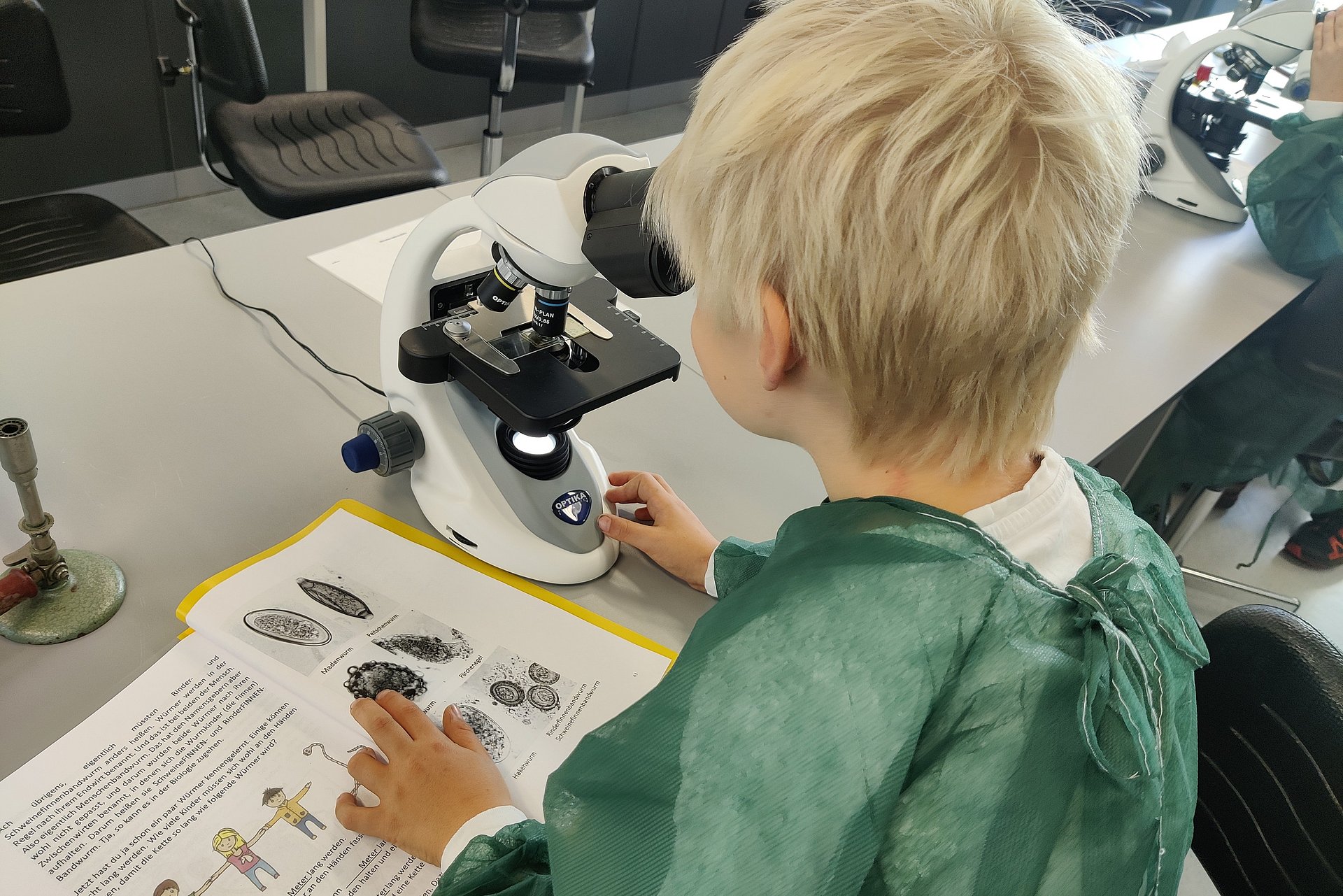 Am Am Institut für Medizinische Mikrobiologie, Immunologie und Hygiene blickt ein Kind durch ein Mikroskop, um Eier von Bandwürmen zu identifizieren.