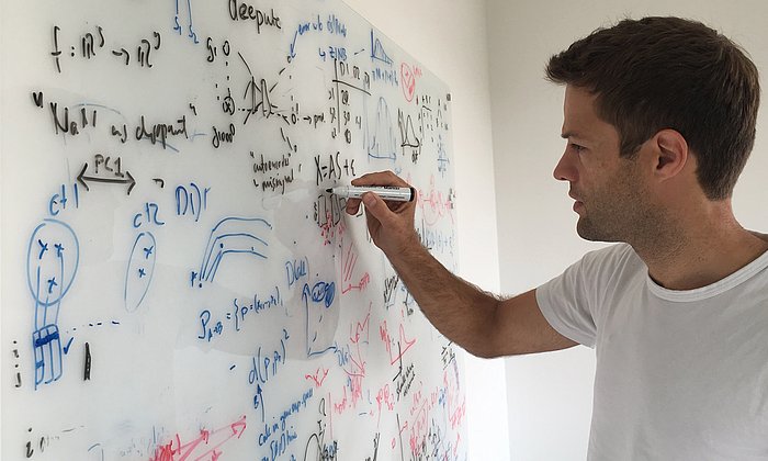 The picture shows Prof. Fabian Theis writing formulas on a blackboard.