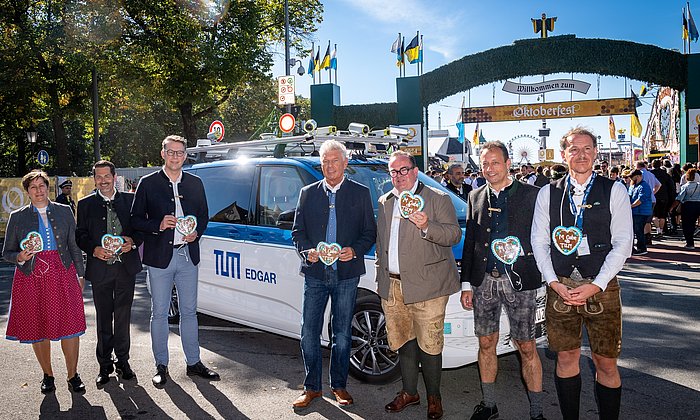 Invited guests in front of the Wiesn Shuttle, the Oktoberfest can be seen in the background