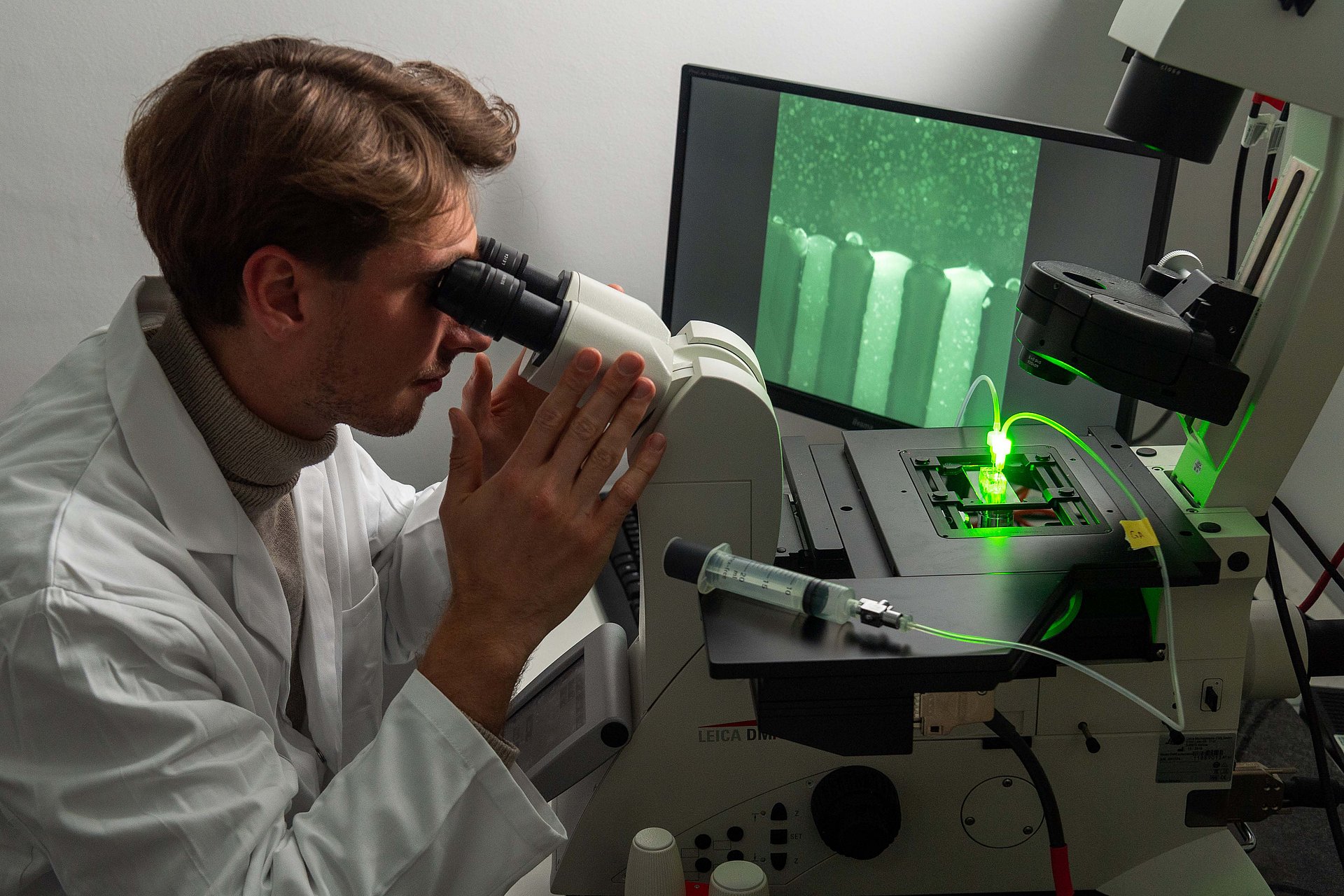 Researchers examine mucin interfaces with microfluidic chips. In this setup, green fluorescent nanoparticles are penetrating the mucin gel.