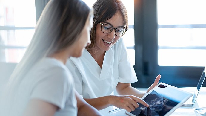 A doctor and a patient are looking at a tablet PC