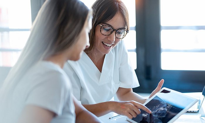 A doctor and a patient are looking at a tablet PC