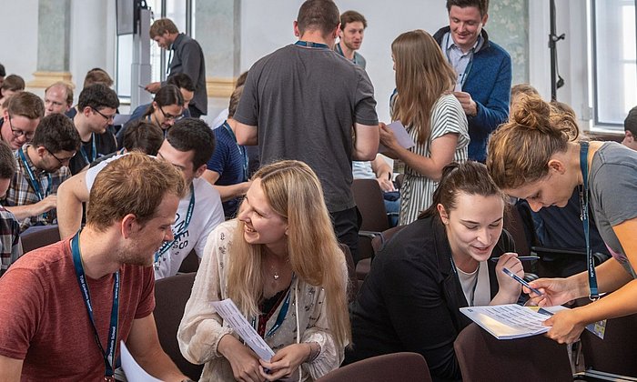 Young researchers chat while seated at a kick-off meeting of the TUM Graduate School.