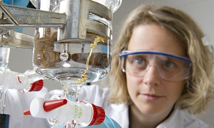 Female chemist wearing safety goggles working on an experiment in the lab.