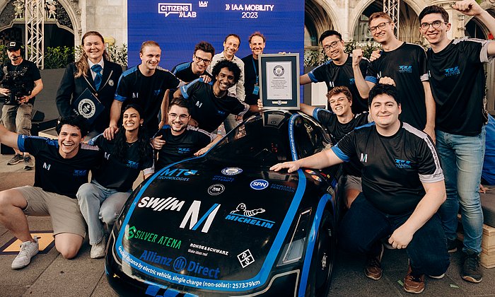 Students stand around a test vehicle celebrating their victory.