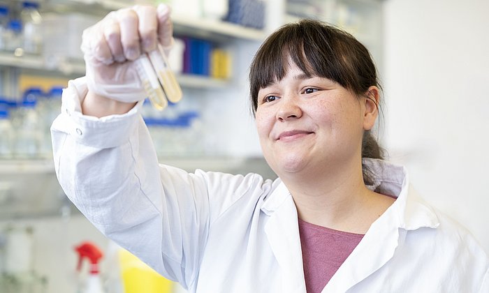 The researcher Ulschan Bathe is examining yeast cultures in test tubes and showing them to the camera.