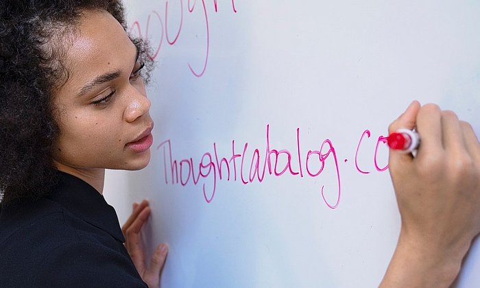 Woman explaining something while writing with a red pen on a whiteboard