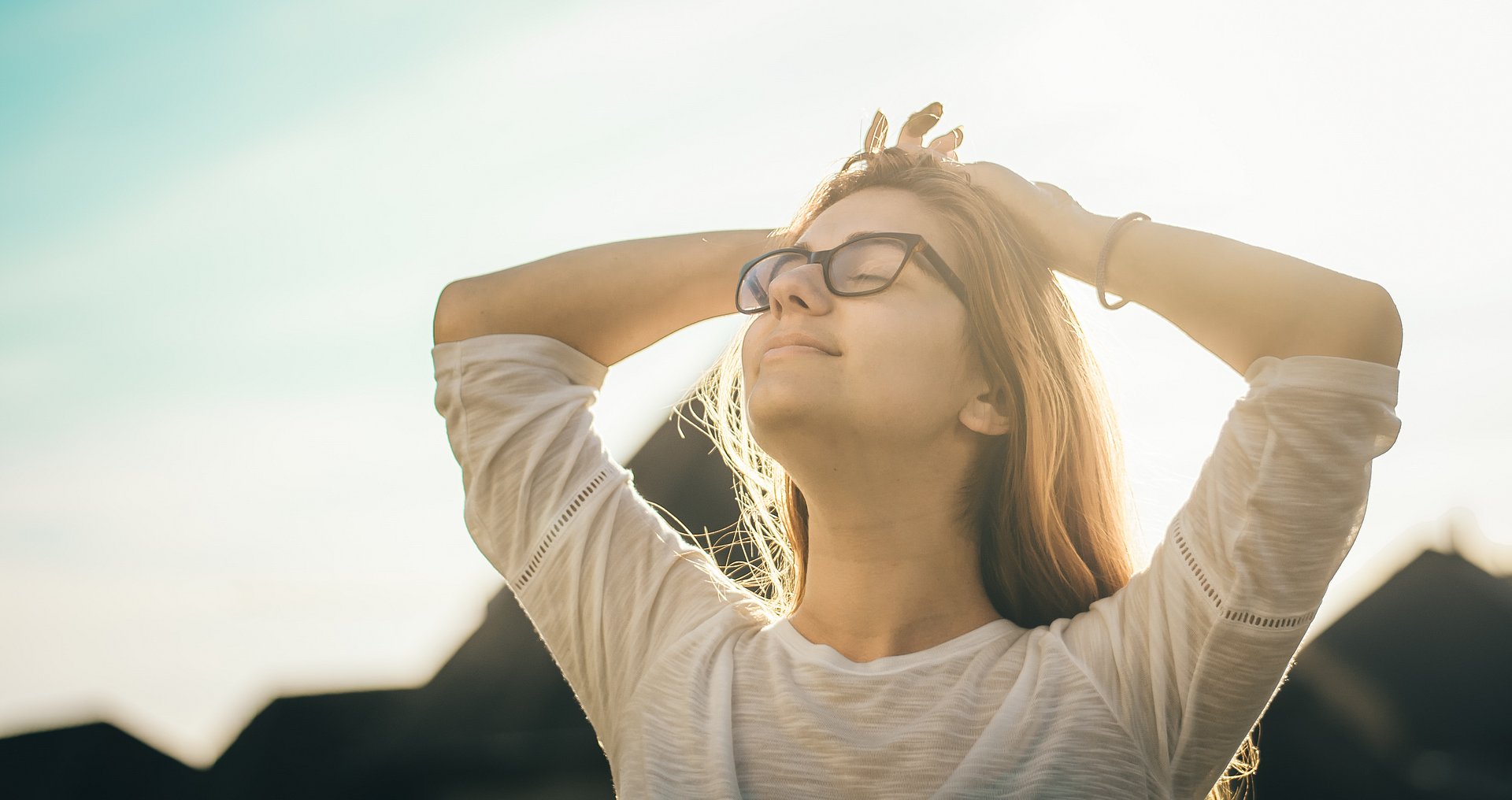 A woman is lying relaxed in the sun, enjoying a peaceful moment – symbolic image for Mental Health Day.