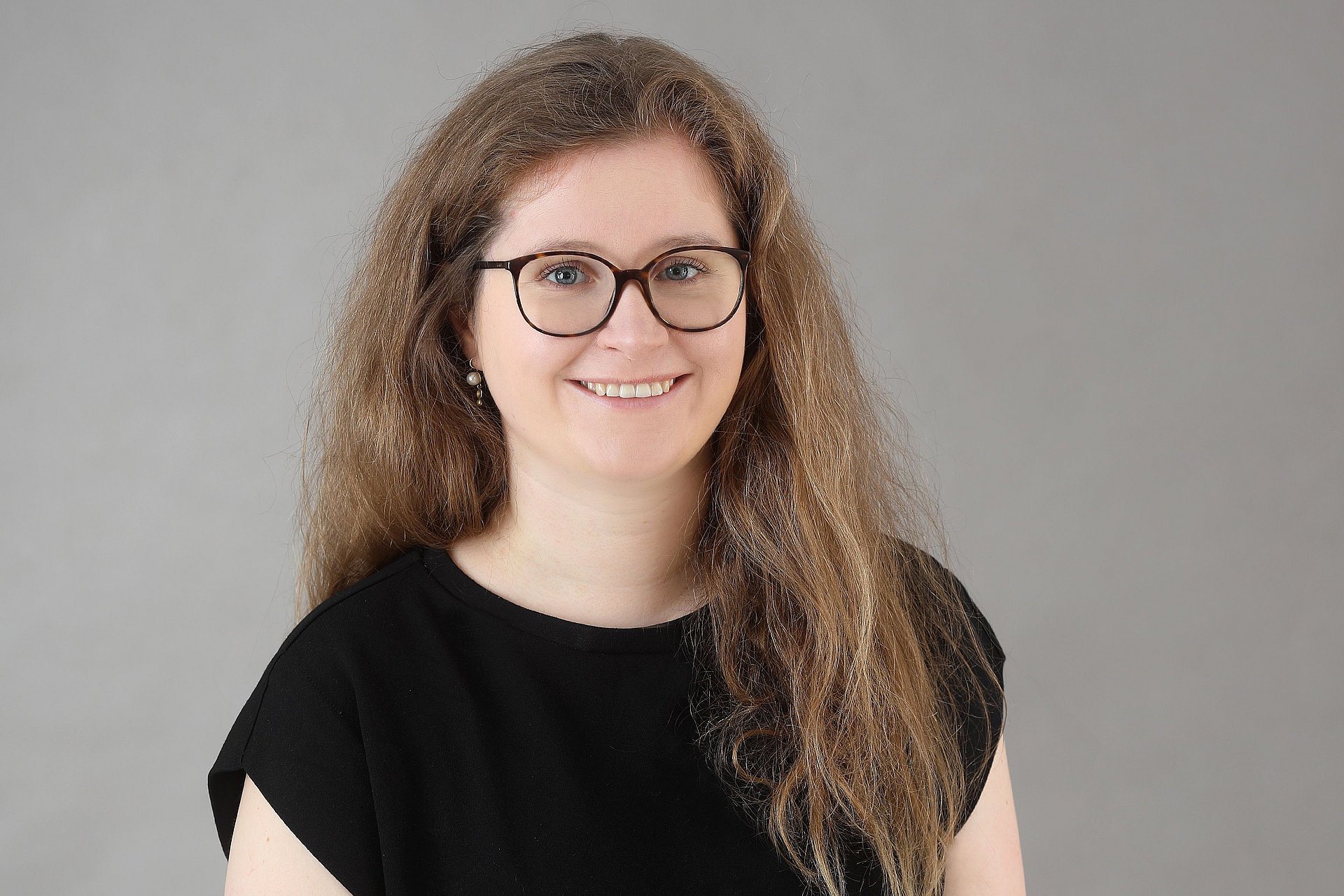 Woman with glasses and long hair looks kindly into the camera