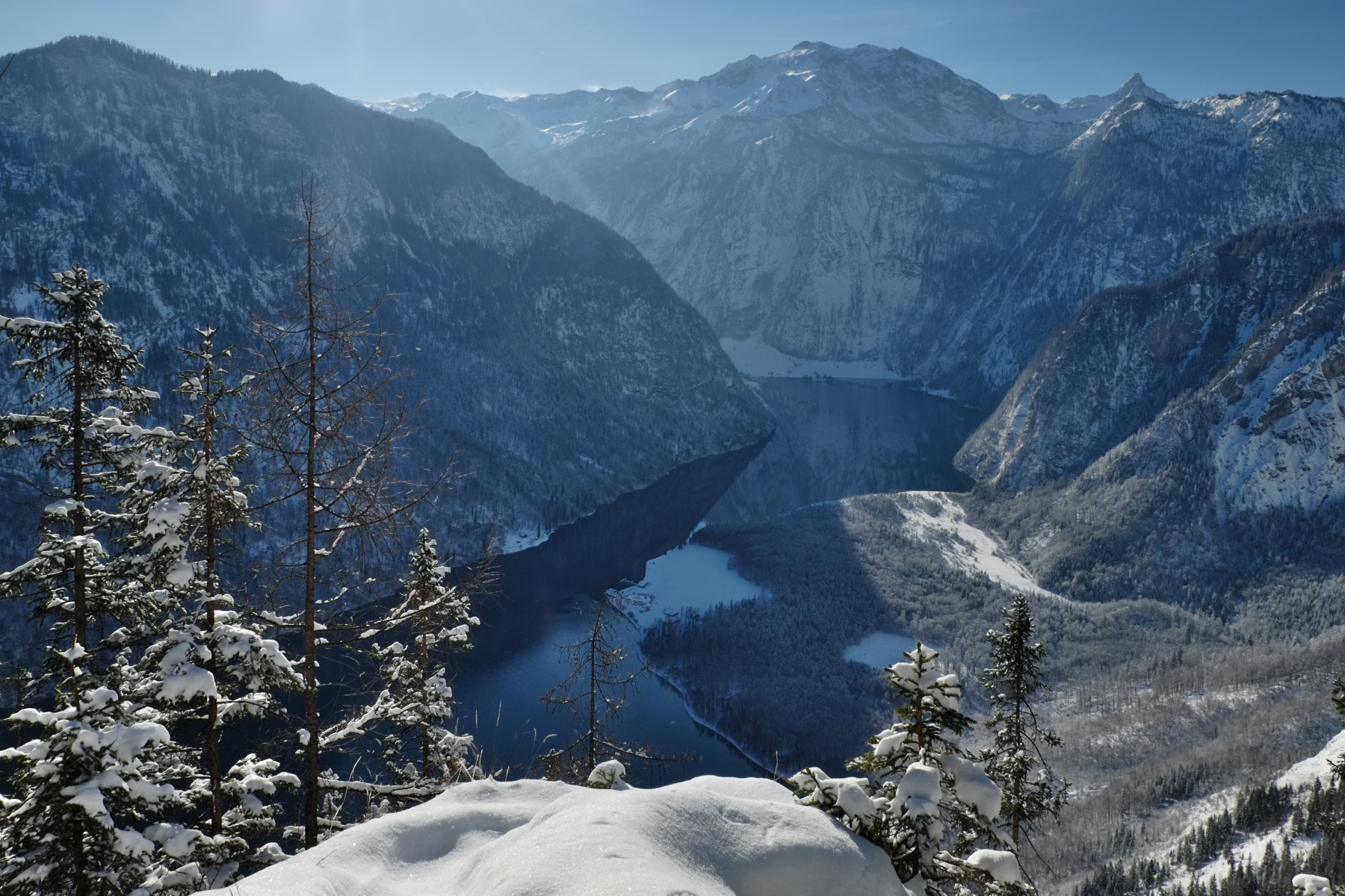 View of Lake Königssee in Bavaria, set in the winter mountains with snow-covered trees.